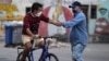 Dos hombres se estrechan la mano en una calle de La Habana, en medio de una ola de contagios de coronavirus. (YAMIL LAGE / AFP)