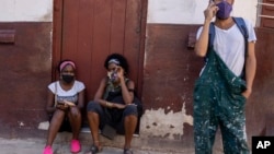 Las personas usan máscaras durante la pandemia de COVID-19 afuera de una tienda de comestibles donde esperan que abra en La Habana. (AP Foto/Ramón Espinosa)