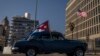 Foto Archivo. Un carro con la bandera cubana pasa frente a la Embajada de Estados Unidos en Cuba.