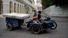 Una familia transporta un colchón en una motocicleta por las calles de La Habana.