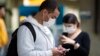 Pasajeros usando mascarillas como precaución contra el contagio del nuevo coronavirus usan sus teléfonos en el Aeropuerto Internacional de Sao Paulo, Brasil.