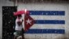 Una mujer que usa una máscara para frenar la propagación del nuevo coronavirus camina por una calle de La Habana. (YAMIL LAGE / AFP)
