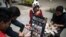 Una pareja de migrantes venezolanos pinta billetes en las calles de Bogotá para protestar contra la situación económica de su país. (Iván Valencia / AFP).