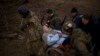 Soldados y milicianos ucranianos cargan a una mujer bajo ataques de artillería rusa en Irpin en las afueras de Kyiv, Ucrania, el 7 de marzo de 2022.