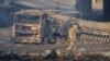 Un soldado ucraniano se desplaza entre los restos de un camión militar incendiado en una calle en Kiev, Ucrania, el sábado 26 de febrero de 2022. (AP Foto/Efrem Lukatsky)