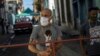 Hombres montan guardia en una reja que corta el acceso a su vecindario en cuarentena por coronavirus, en La Habana, para mantener alejados a los que no viven allí. (AP/Ramon Espinosa)