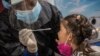 Una empleada de salud toma una muestra para una prueba de COVID-19 a una niña procedente de México, en el Aeropuerto Internacional José Martí de La Habana.